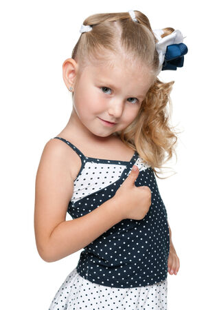 A little girl in a fashion dress holds her thumb up against the white backgroundの写真素材