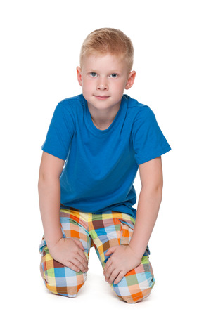 A smiling young boy in a blue shirt is sitting on the white backgroundの写真素材