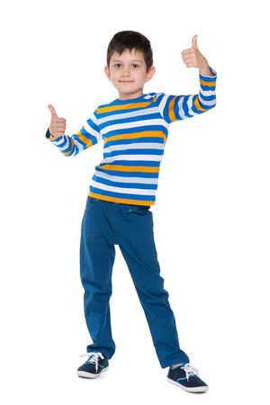 A cute young boy holds his thumbs up against the white backgroundの写真素材