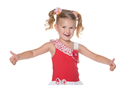 A laughing little girl holds her thumbs up against the white backgroundの写真素材