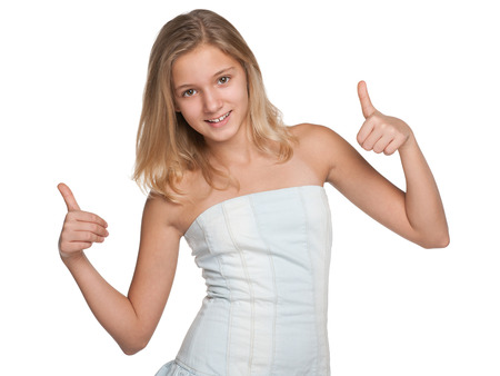 A preteen girl holds her thumbs up against the white backgroundの写真素材