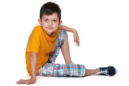 A smiling little boy in a yellow shirt is sitting on the white backgroundの写真素材