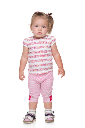 A thoughtful baby girl stands on the white backgroundの写真素材