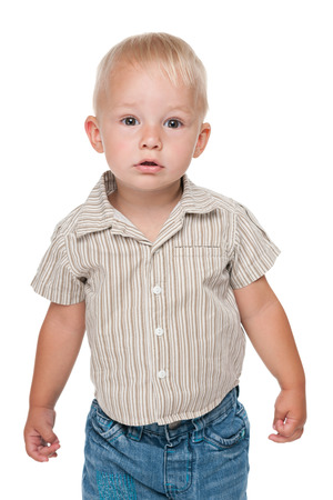 A serious baby boy stands against the white backgroundの写真素材