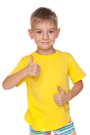 A smiling little boy holds his thumbs up on the white backgroundの写真素材