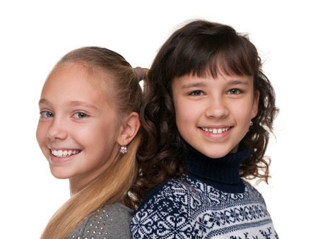 Two happy girls are standing together against the white backgroundの写真素材