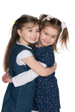 A portrait of two hugging little girls on the white の写真素材