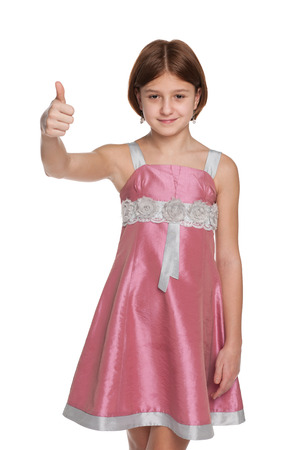 A smiling preteen girl holds her thumb up on the white の写真素材