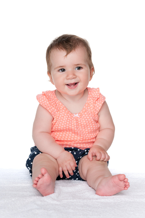 A smiling baby girl sits on the white towelの写真素材