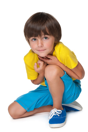 A smiling little boy in a yellow shirt sits on the white の写真素材