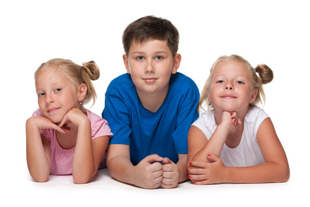 Group of three children are lying on the floor on the white の写真素材