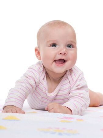 A happy baby girl is lying on the white towelの写真素材
