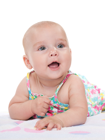 An adorable happy baby girl is lying on the white towelの写真素材