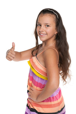 A smiling preteen girl holds her thumb up against the white の写真素材