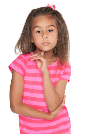 A thoughtful pretty little girl stands on the white の写真素材