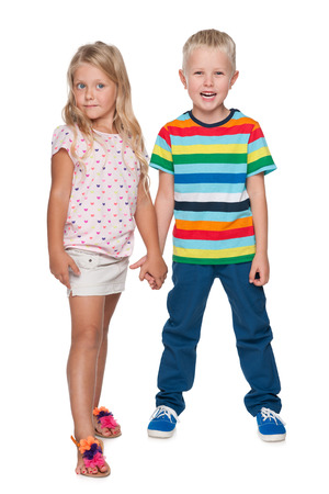 Two little blond children are standing against the white の写真素材