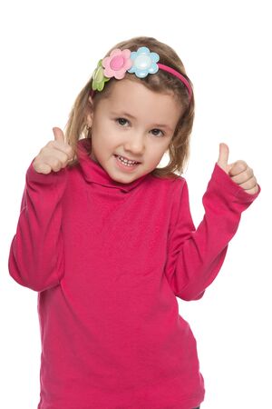 A cute small girl holds his thumbs up on the white の写真素材