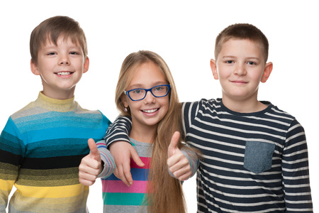 Three cheerful children stand together on the white backgroundの写真素材