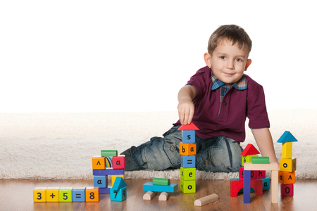A little boy plays with toys on the white carpetの写真素材