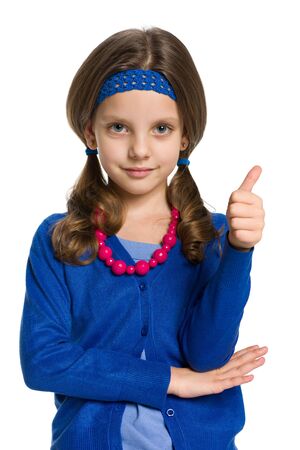 A smiling little girl holds her thumb up on the white backgroundの写真素材
