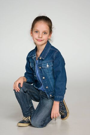 A smiling little girl is sitting on the gray backgroundの写真素材