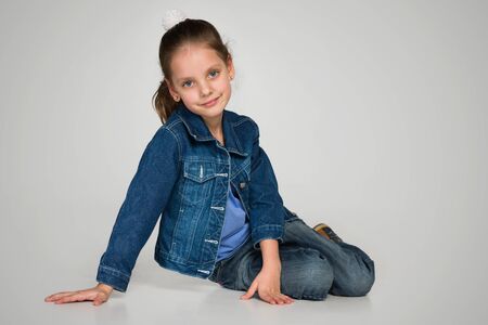 A smiling little girl sits on the gray backgroundの写真素材