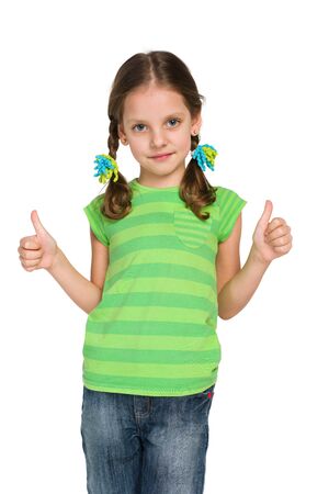 A pretty little girl holds her thumbs up against the white backgroundの写真素材