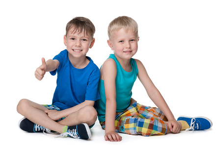 Two little boys sit together on the white backgroundの写真素材