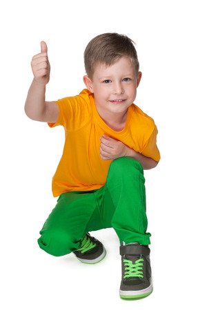 A little boy holds his thumb up against the white backgroundの写真素材