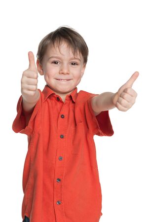 Young boy in the red shirt holds his thumbs up on the white backgroundの写真素材