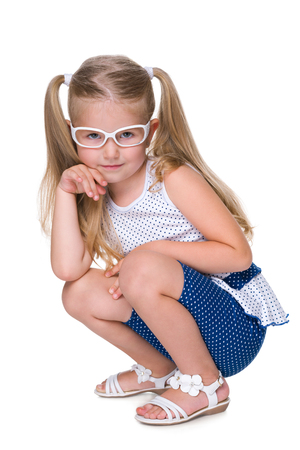 A pretty little girl in glasses is sitting on the floorの写真素材