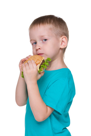 Little boy eats hamburger on the white backgroundの写真素材