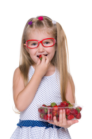 A cute little girl eats strawberry on the white backgroundの写真素材
