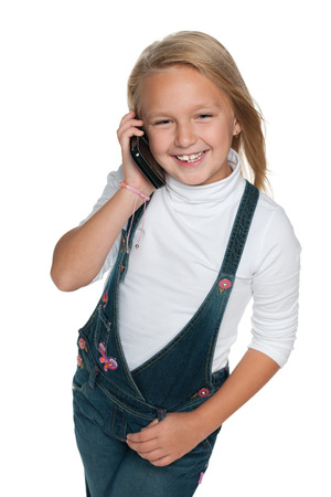 A portrait of a smiling young girl with a cell phone on the white backgroundの写真素材