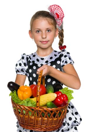 A pretty young girl holds a basket with vegetables against the white backgroundの写真素材