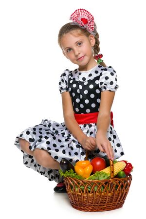 A pretty little girl with a basket of vegetables against the white backgroundの写真素材