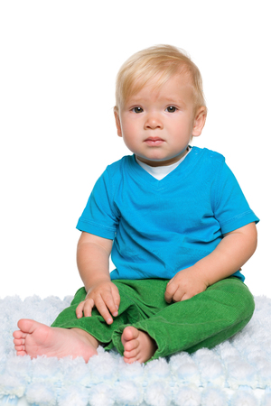 A baby boy sits on the white carpetの写真素材