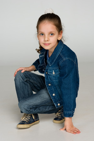 A pretty little girl sits on the gray backgroundの写真素材