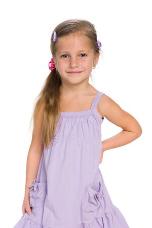 A smiling little girl stands against the white backgroundの写真素材