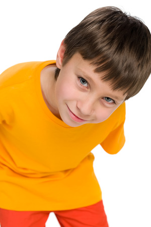 A smiling little boy in the yellow shirt stands against the white backgroundの写真素材