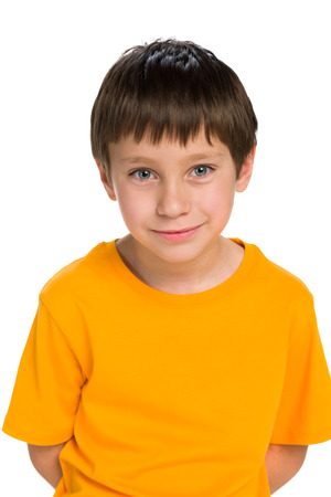 A smiling little boy in the yellow shirt stands against the white backgroundの写真素材