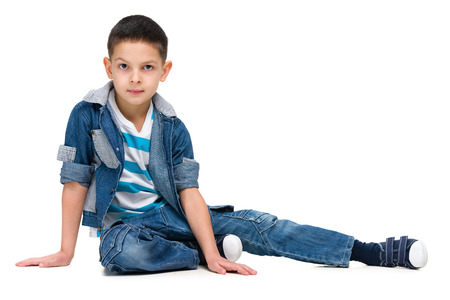 A serious little boy sits on the white backgroundの写真素材