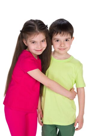 Two smiling children stand together against the whiteの写真素材