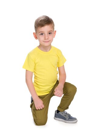 A smiling little boy in the yellow shirt is sitting on the white backgroundの写真素材