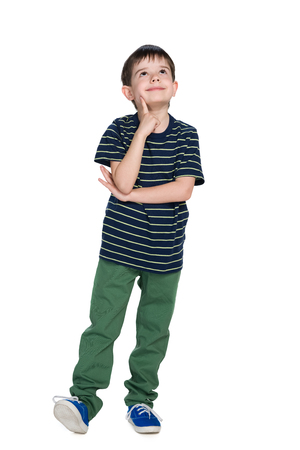 A cute little boy in a striped shirt looks up against the white backgroundの写真素材