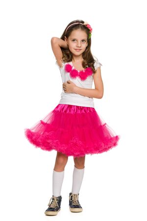 A pretty little girl is standing against the white backgroundの写真素材