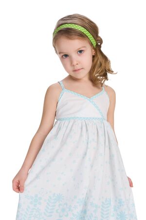 A serious little girl stands on the white backgroundの写真素材