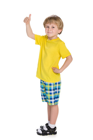 A blond little boy holds his thumb up on the white backgroundの写真素材