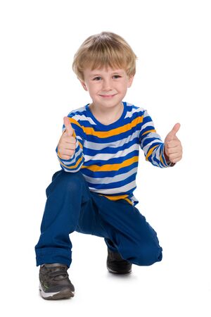 A smiling little boy holds his thumb up against the white backgroundの写真素材