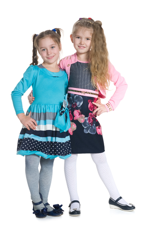 Two happy girls are standing together against the white backgroundの写真素材